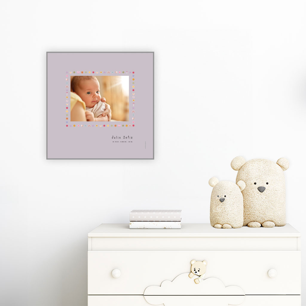 viser kvadratisk-foedselstavle med et foto-fornavn-foedselsdata-paa-lilla-baggrund-med kant-af-fine-smaa-illustrationer-designet af www.plakatcompagniet.dk. plakaten haenger over en hvid kommode paa et boernevaerelse
