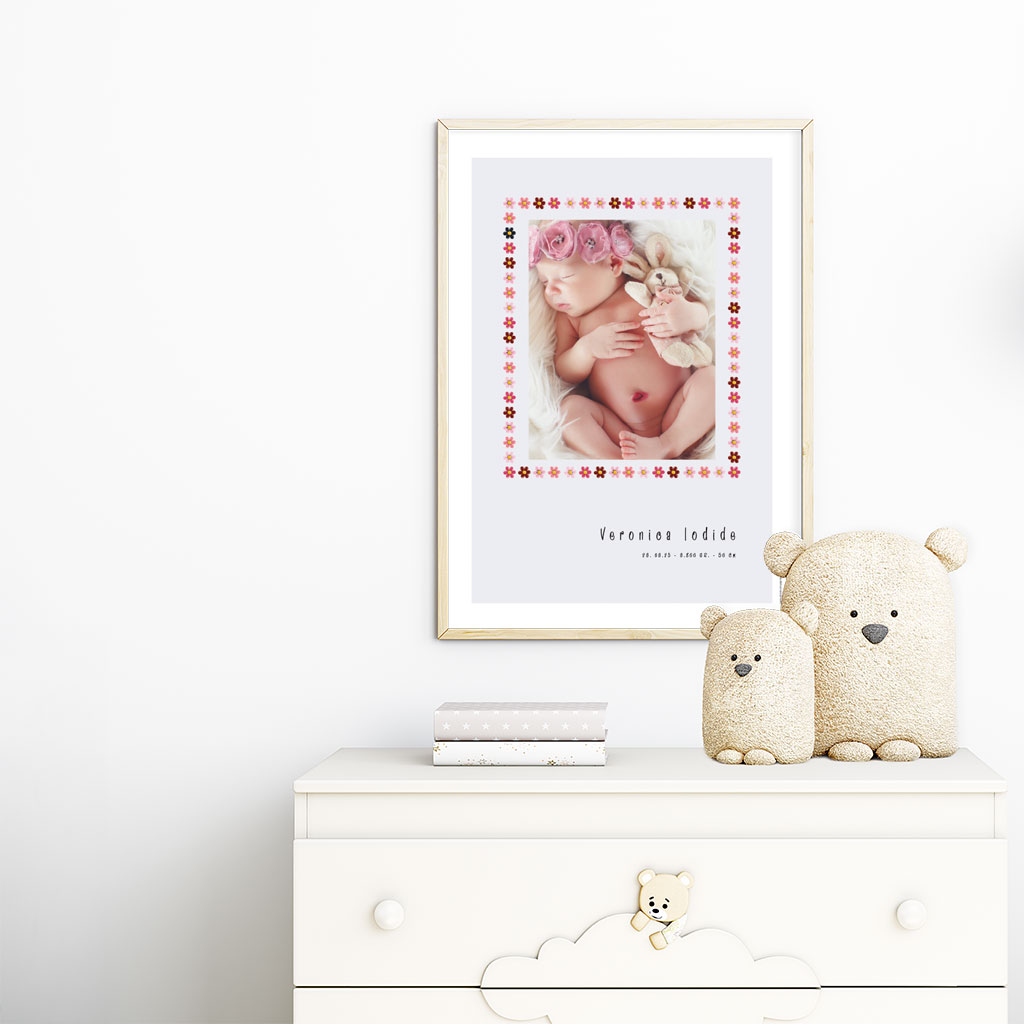 viser rektangulaer fødselstavle med et foto omkranset af en soed kant af blomster i rosa farver. Dertil fornavn og foedselsdata. Graa baggrund med hvid kant. Designet af www.plakatcompagniet.dk x