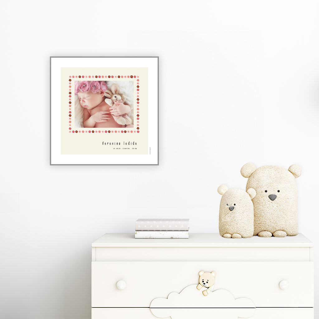 viser kvadratisk fødselstavle med et foto omkranset af en kant af lyseroede blomster illustrationer. Dertil fornavn og foedselsdata paa beige baggrund og med hvid kant.. Designet af www.plakatcompagniet.dk. plakat haenger paa boernevaerelse over hvid kommode