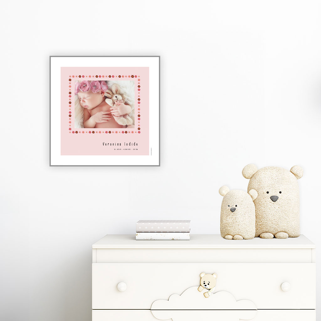viser kvadratisk fødselstavle med et foto omkranset af en kant af lyseroede blomster illustrationer. Dertil fornavn og foedselsdata paa lyseroed baggrund og med hvid kant.. Designet af www.plakatcompagniet.dk. plakat haenger paa boernevaerelse over hvid kommode