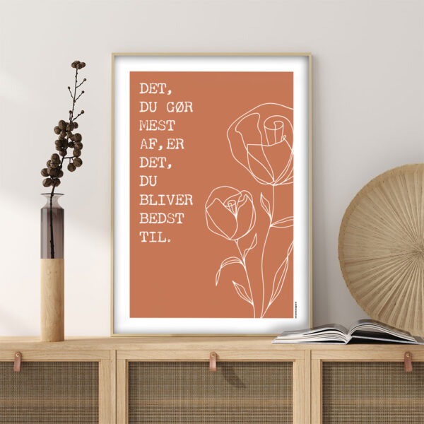 viser citatplakaten med citatet "Det du goer mest af er det du bliver bedst til" på orange baggrund fra www.plakatcompagniet.dk
